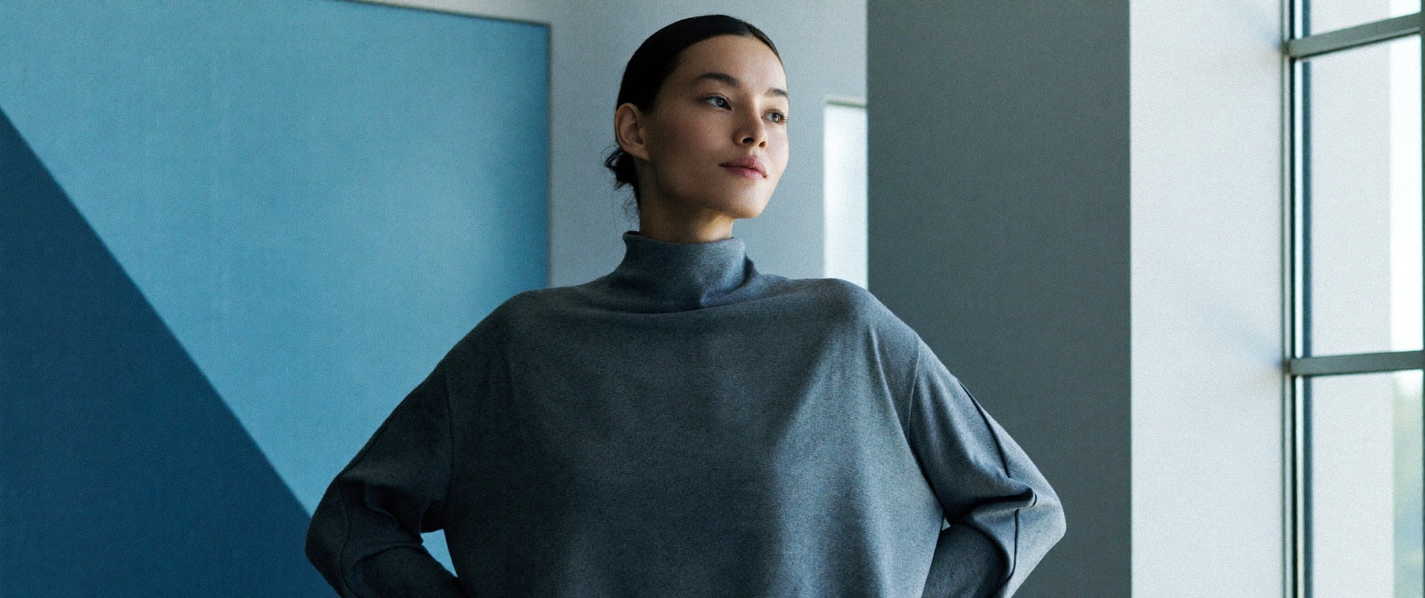 A poised woman at ease, relaxed shoulders, in a bright modern interior